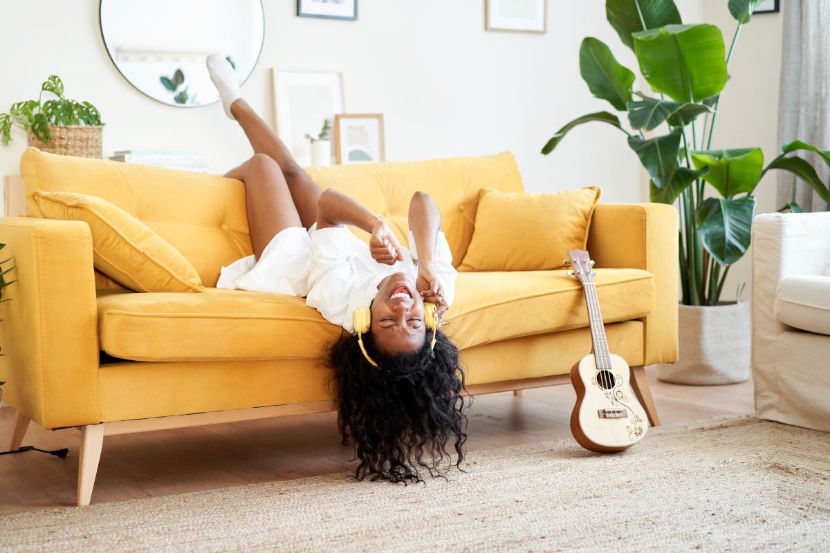 Une jeune femme afro-américaine chante motivée sur le canapé de la maison.